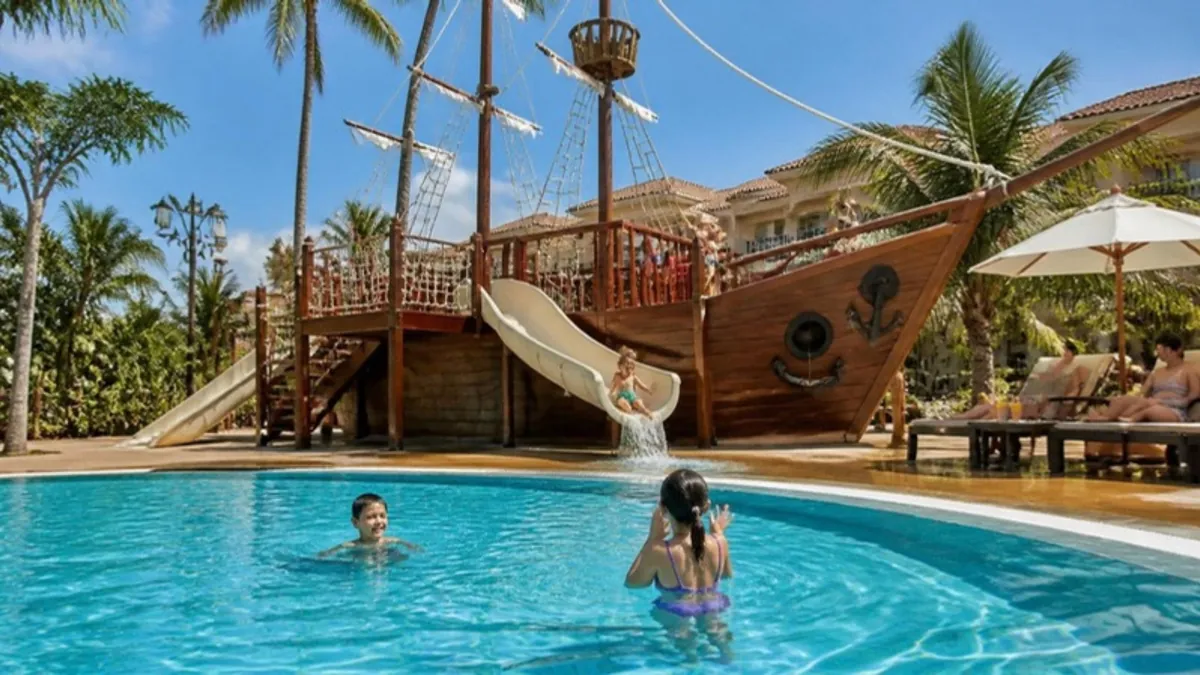 Wooden pirate-ship playground beside a swimming pool at a family hotel